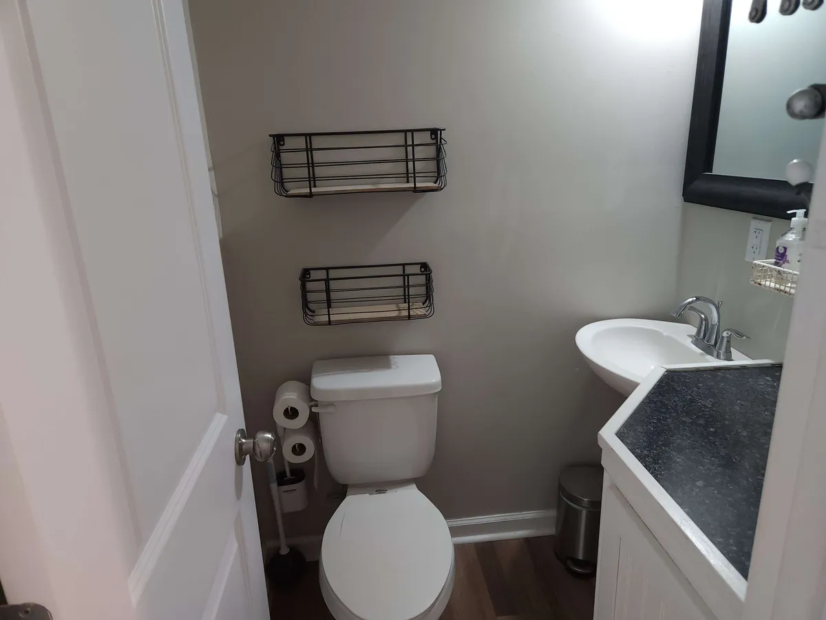 A compact half bath with a toilet, sink, and mirror, all set against a neutral backdrop. The simple, functional design is perfect for quick freshening up.
