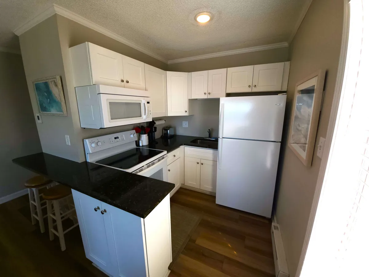 A view of the newly remodeled kitchen featuring a spacious countertop, sleek white cabinetry, and modern black appliances. The setting is inviting and cozy, suggesting a perfect place for preparing special meals together.