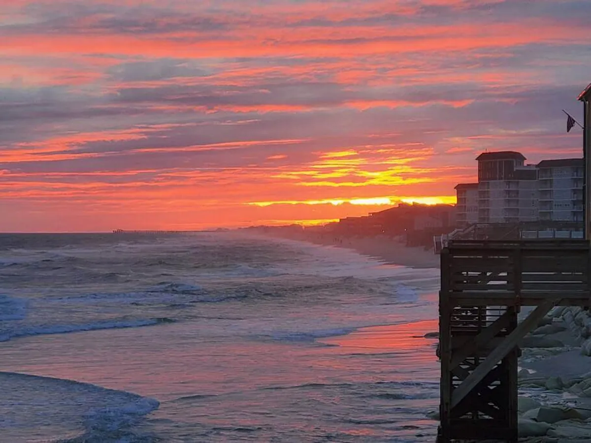 A vibrant sunset over the ocean, with a pier extending into the water and gentle waves washing onto the shore. The sky is filled with warm colors, creating a serene and romantic ambiance, ideal for evening walks or simply unwinding together.